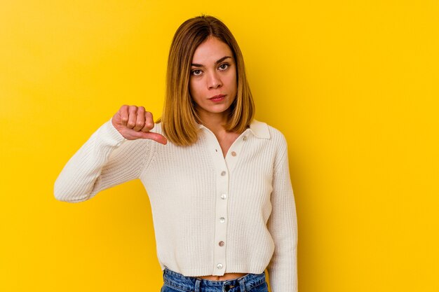 Joven mujer caucásica flaca aislada en amarillo mostrando un gesto de aversión, pulgares hacia abajo. Concepto de desacuerdo.