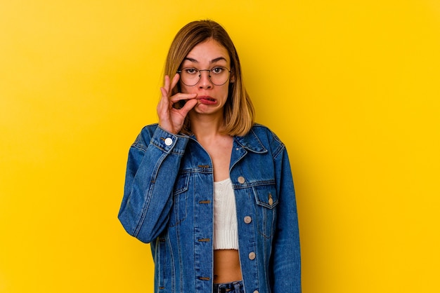 Joven mujer caucásica flaca con los dedos en los labios guardando un secreto.