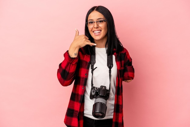 Joven mujer caucásica de fotografía con un brazo aislado sobre fondo rosa mostrando un gesto de llamada de teléfono móvil con los dedos.