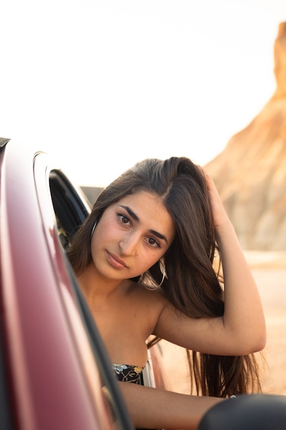 Joven mujer caucásica fuera de la ventana de un coche en el desierto de las Bardenas Reales. Navarra, País Vasco.