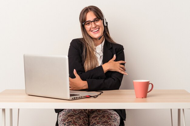 Joven mujer caucásica haciendo teletrabajo aislado sobre fondo blanco que se siente confiado, cruzando los brazos con determinación.