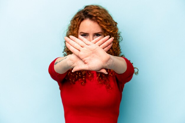 Foto joven mujer caucásica de jengibre aislada de fondo azul haciendo un gesto de negación