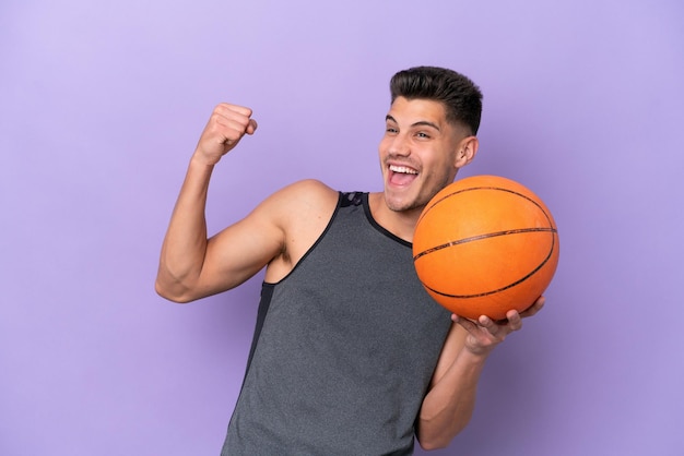 Joven mujer caucásica jugador de baloncesto hombre aislado sobre fondo púrpura celebrando una victoria