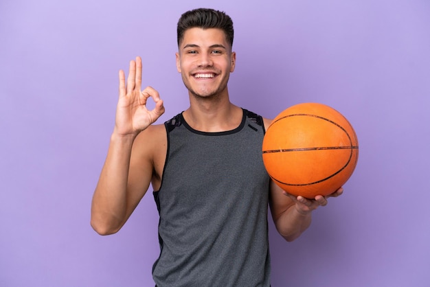 Joven mujer caucásica jugador de baloncesto hombre aislado sobre fondo púrpura mostrando signo ok con los dedos