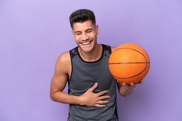 Joven mujer caucásica jugador de baloncesto hombre aislado sobre fondo púrpura sonriendo mucho