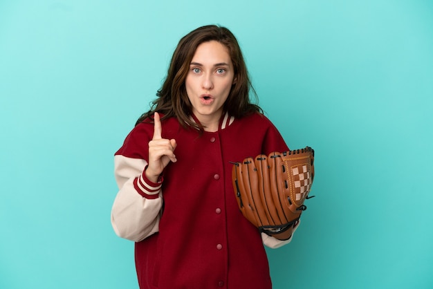 Joven mujer caucásica jugando béisbol aislado sobre fondo azul con la intención de darse cuenta de la solución mientras levanta un dedo hacia arriba