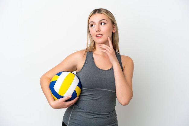Joven mujer caucásica jugando voleibol aislada de fondo blanco pensando en una idea mientras mira hacia arriba