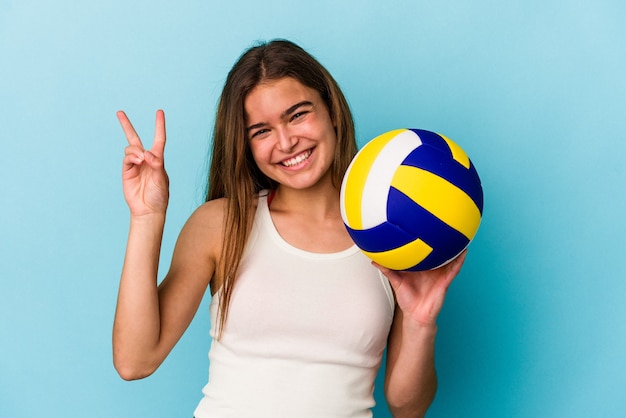 Joven mujer caucásica jugando voleibol aislado sobre fondo azul mostrando el número dos con los dedos.