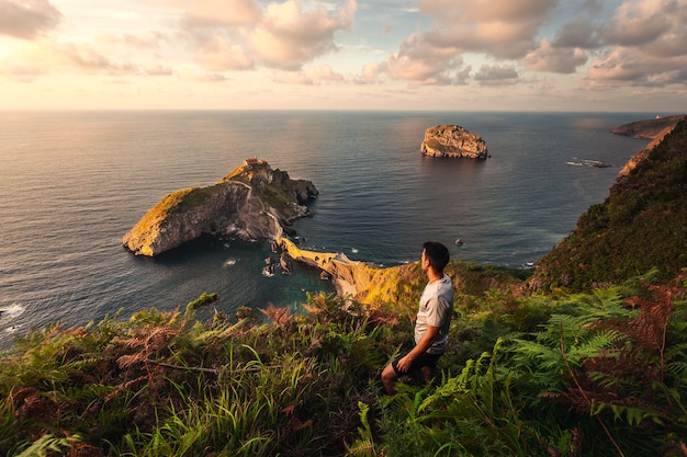 Joven mujer caucásica mirando al ermitage de Gaztelugatxe en la costa del País Vasco.