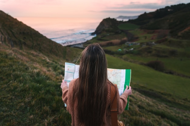 Foto joven mujer caucásica mirando un mapa en un parque natural junto a la costa