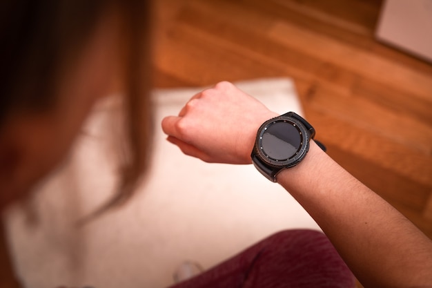 Foto joven mujer caucásica mirando el reloj deportivo mientras hace ejercicios en casa