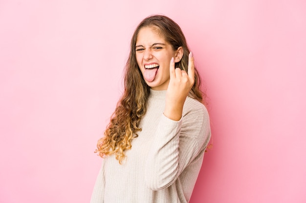 Joven mujer caucásica mostrando gesto de rock con los dedos