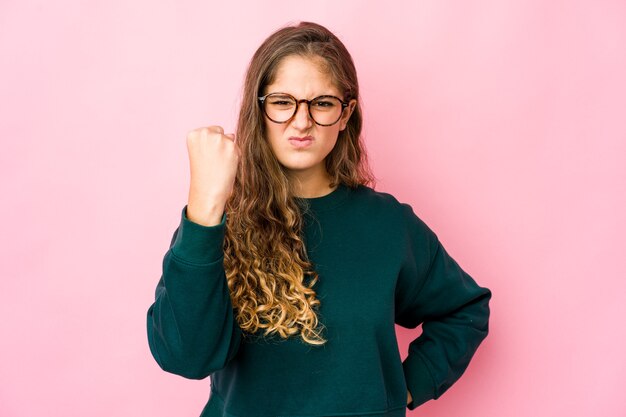 Joven mujer caucásica mostrando puño, expresión facial agresiva.