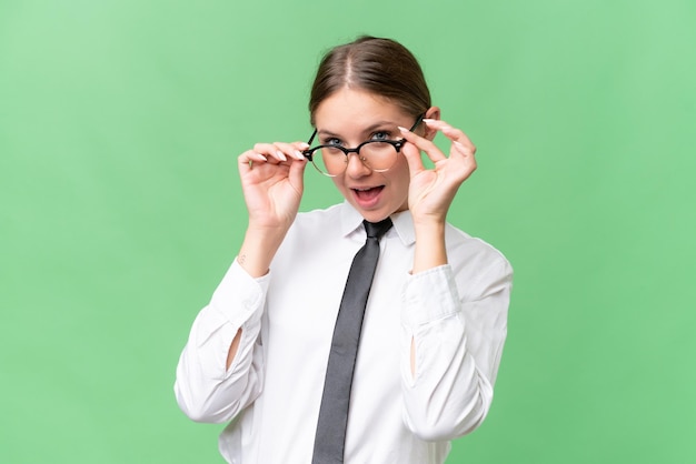 Joven mujer caucásica de negocios sobre un fondo aislado con gafas y sorprendida