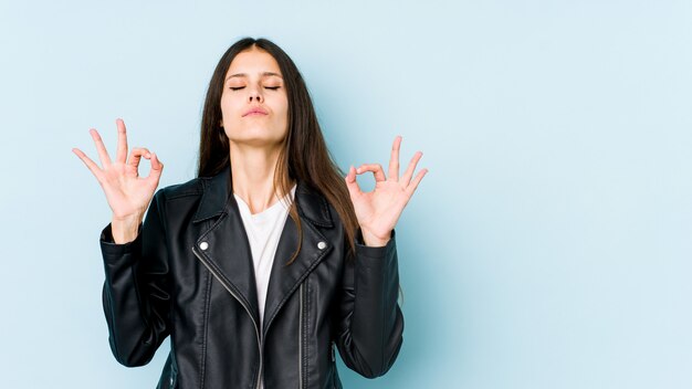 Joven mujer caucásica en la pared azul se relaja después de un duro día de trabajo