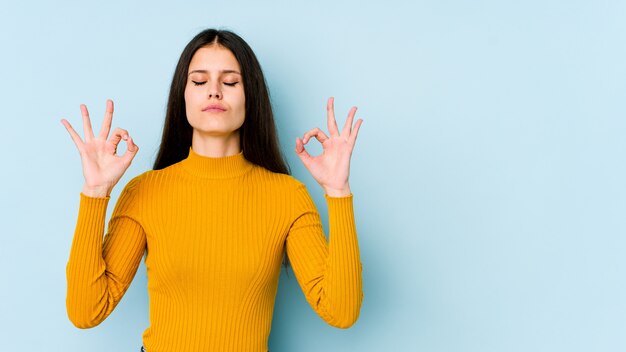 Joven mujer caucásica en la pared azul se relaja después de un duro día de trabajo