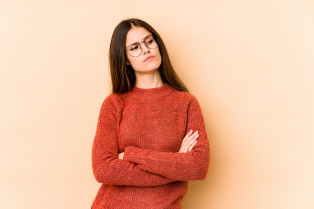 Joven mujer caucásica en pared beige soñando con alcanzar objetivos y propósitos