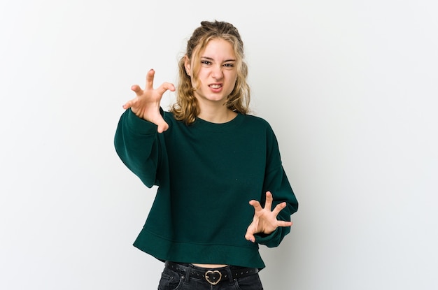 Joven mujer caucásica en la pared blanca mostrando garras imitando un gato, gesto agresivo.