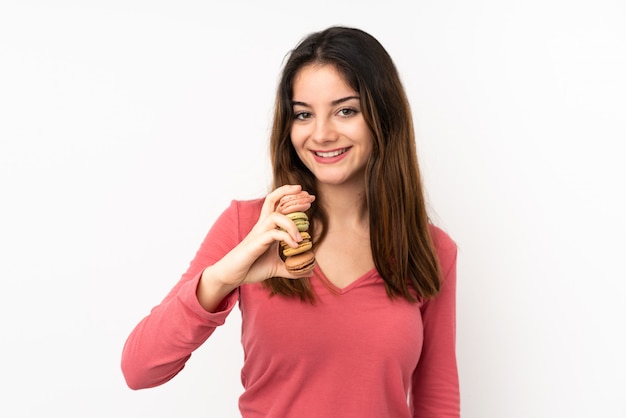 Joven mujer caucásica en pared rosa con coloridos macarons franceses y con expresión feliz