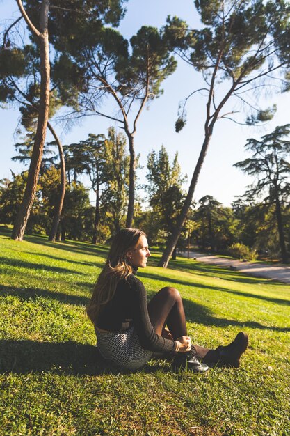 Joven mujer caucásica en el parque vistiendo un pantalón blanco y una camisa negra. Madrid, España.