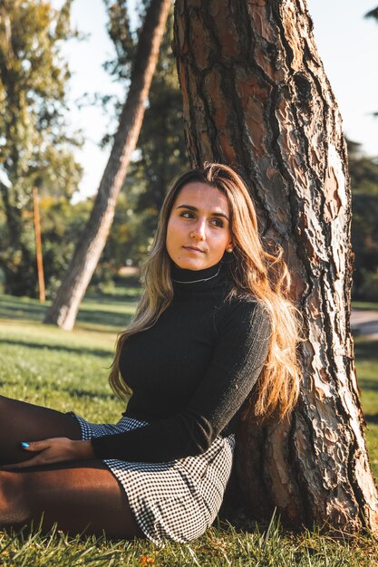 Joven mujer caucásica en el parque vistiendo un pantalón blanco y una camisa negra. Madrid, España.