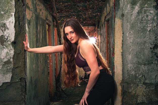 Joven mujer caucásica en un pasillo de un edificio en ruinas en medio del bosque.