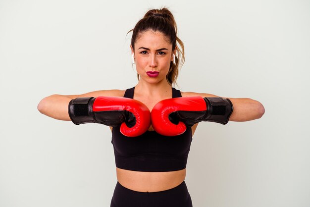 Joven mujer caucásica peleando con guantes de boxeo aislado sobre fondo blanco.