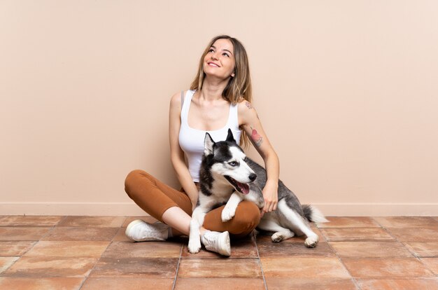 Foto joven mujer caucásica con perro sobre pared aislada