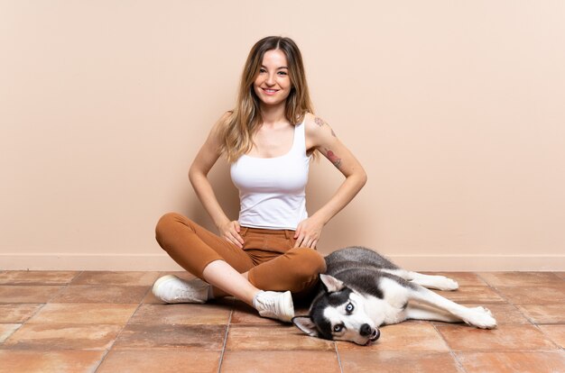 Joven mujer caucásica con perro sobre pared aislada