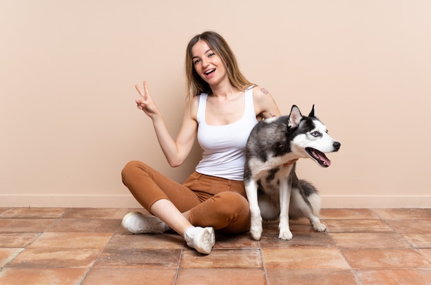 Joven mujer caucásica con perro sobre pared aislada