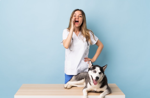 Joven mujer caucásica con perro sobre pared aislada