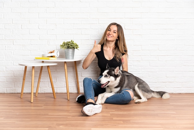 Joven mujer caucásica con perro sobre pared aislada