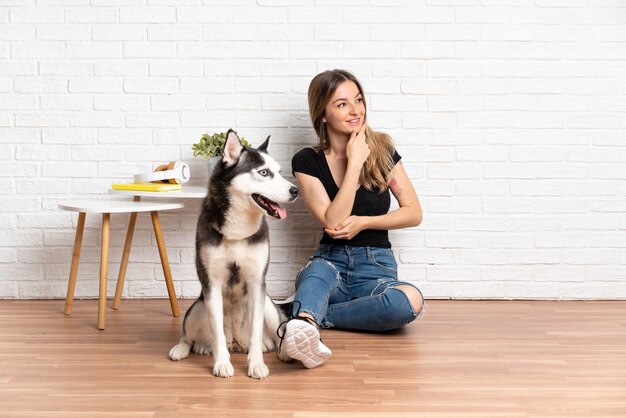 Joven mujer caucásica con perro sobre pared aislada