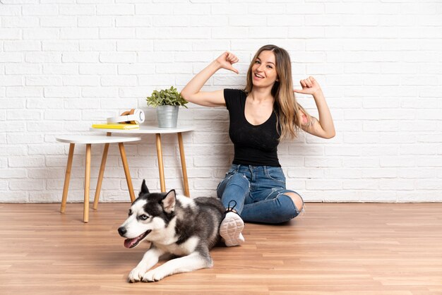 Joven mujer caucásica con perro sobre pared aislada