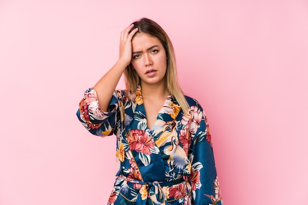 Foto joven mujer caucásica en pijama cansada y con mucho sueño manteniendo la mano en la cabeza.