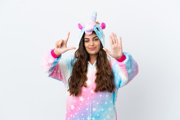 Joven mujer caucásica con un pijama de unicornio aislado de fondo blanco contando siete con los dedos
