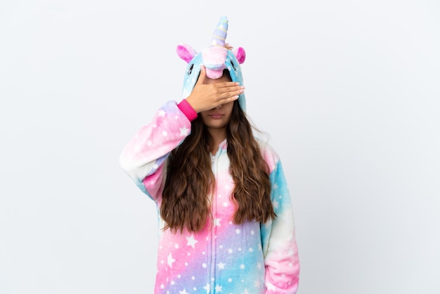 Joven mujer caucásica con un pijama de unicornio aislado de fondo blanco cubriendo los ojos con las manos No quiero ver algo