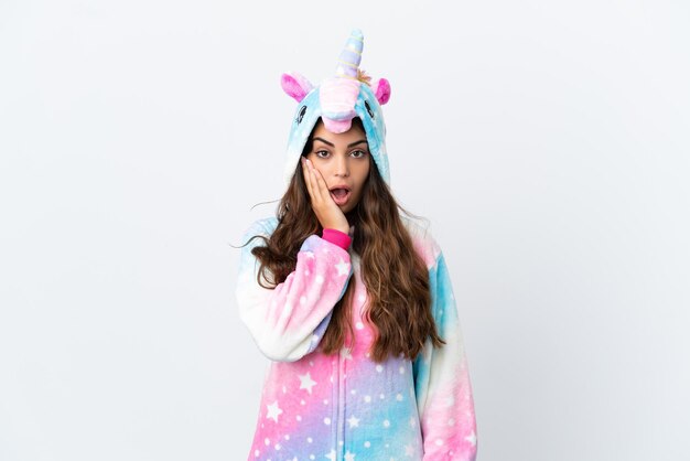 Joven mujer caucásica con un pijama de unicornio aislado de fondo blanco con expresión facial sorprendida y sorprendida