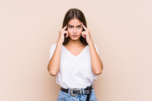 Joven mujer caucásica posando aislada se centró en una tarea, manteniendo los índices apuntando con la cabeza.