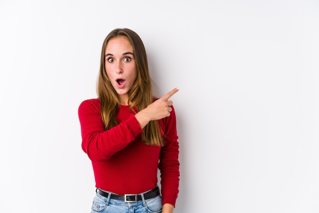 Joven mujer caucásica posando aislado apuntando hacia el lado