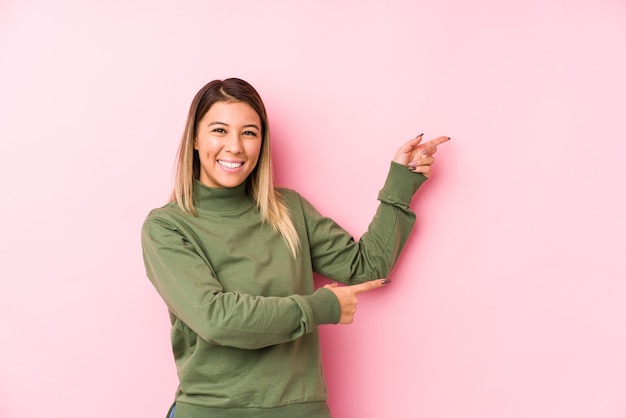 Joven mujer caucásica posando aislado emocionado señalando con los dedos índices de distancia.