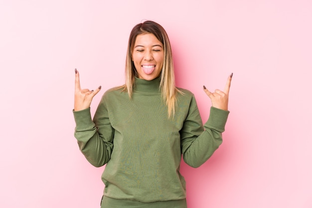 Joven mujer caucásica posando aislado mostrando gesto de rock con los dedos