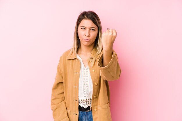 Joven mujer caucásica posando aislado mostrando puño, expresión facial agresiva.