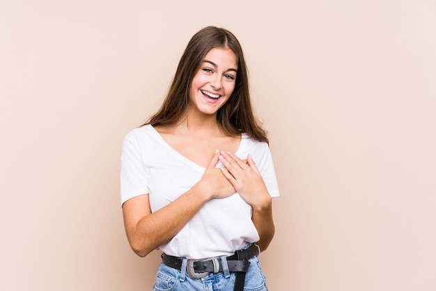 Joven mujer caucásica posando aislado riendo manteniendo las manos en el corazón, concepto de felicidad.