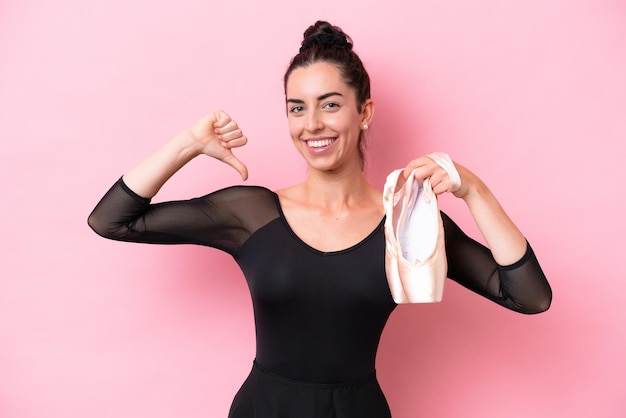 Joven mujer caucásica practicando ballet aislado sobre fondo rosa orgullosa y satisfecha