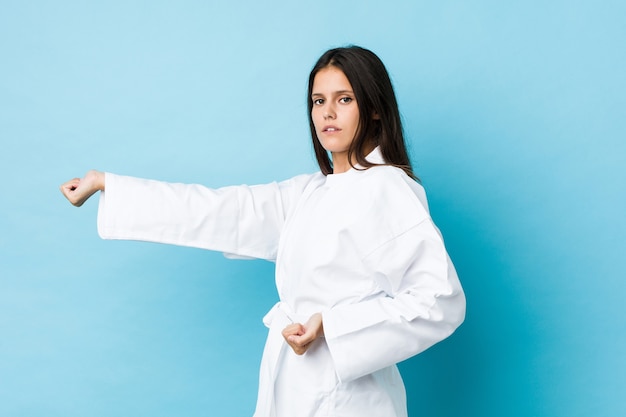 Joven mujer caucásica practicando karate aislado en un espacio azul