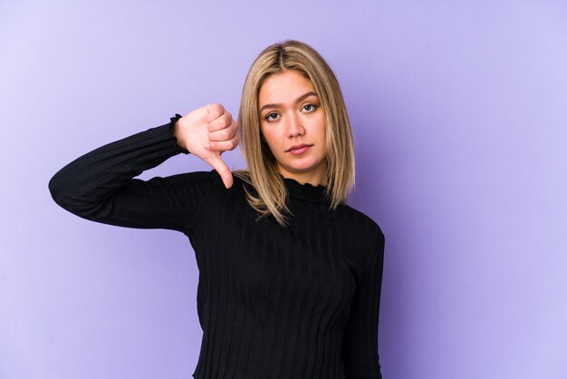 Joven mujer caucásica rubia aislada mostrando un gesto de aversión, pulgares hacia abajo. Concepto de desacuerdo.