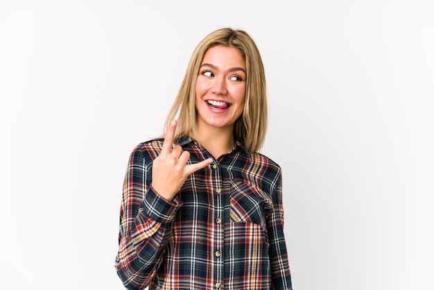 Joven mujer caucásica rubia aislada mostrando gesto de rock con los dedos