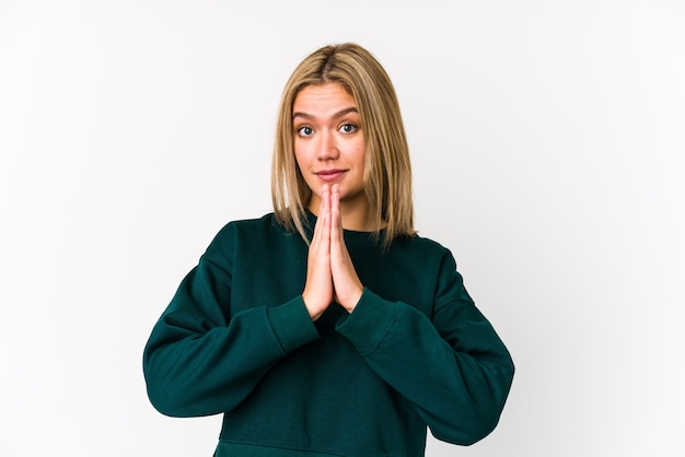 Joven mujer caucásica rubia aislada rezando, mostrando devoción, persona religiosa en busca de inspiración divina.