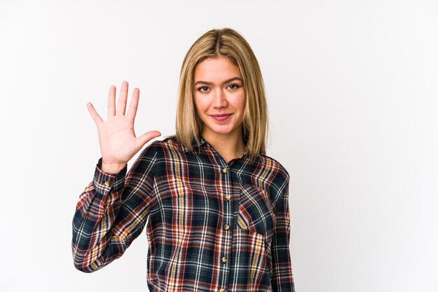 Joven mujer caucásica rubia aislada sonriendo alegre mostrando el número cinco con los dedos.